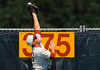 ball player making a leap to catch a baseball before it goes over the fence