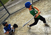 young player swinging for the ball while at bat during a baseball game
