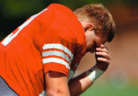 football player taking a moment to kneel and say a quick prayer before a football game