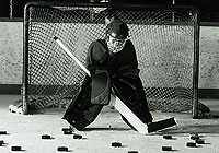 young hockey goalie surrounded by hockey pucks